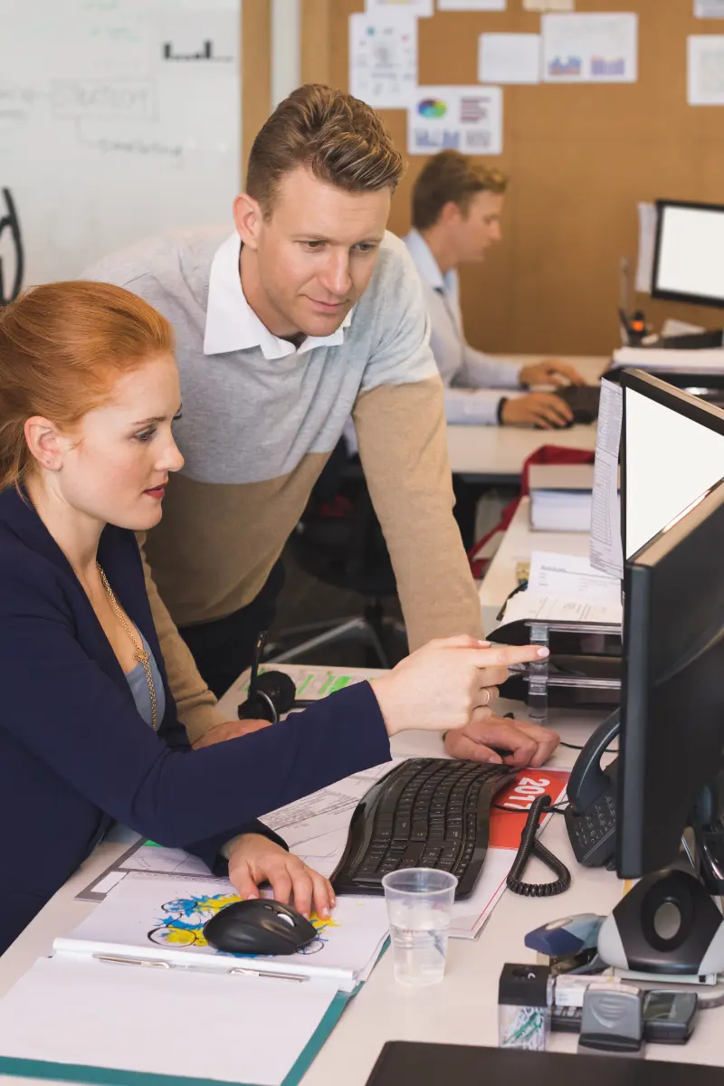 Young businesswoman discussing with male colleague while working in office